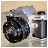 35mm SLR camera with a 50mm Promaster MC lens, with a leather case; appears to be in good condition,
