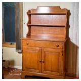 cupboard with two open shelves over a lower section with a full width drawer over two cabinet doors 