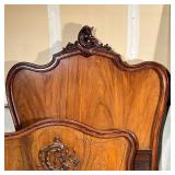 Antique carved wooden bedframe, of nicely figured wood, with carved scrollwork, and with inlaid scre