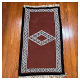 FLAT WOVEN MAT | With a central diamond, and overall diamond and triangle pattern on a brown field -