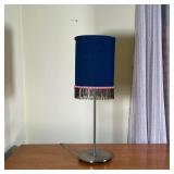 BEADED BEDSIDE LAMP | Small table lamp with beaded tassels hanging from a cylindrical shade, on a me