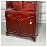 Having two glazed doors before two shelves, over a full-width drawer over lower cabinet doors, of on