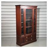 Having three front glazed doors over two drawers flanked by small cabinet doors - h. 64 x w. 38 x d.