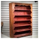 red painted open shelves on the front with a scalloped decorated opening various coats of paint and 