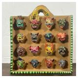 MEXICAN MASK CERAMIC  |  Ceramic wall hanging displaying miniature colorful masks, signed "Ortega" o
