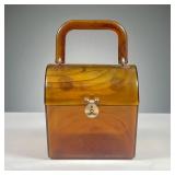 AMBER LUCITE MIDCENTURY HANDBAG | Bakelite type handbag with hinged lid and bail handle. Dimensions: