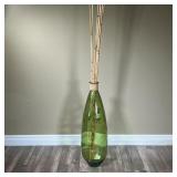 OVERSIZED DECORATIVE JAR | Large green glass jar with tall bamboo sticks sticking out the top. Bambo