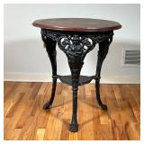CAST IRON PUB TABLE | Distressed wood top on a wrought iron tripod base with figural knees and claw 
