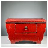 CHINESE LACQUER STOOL | Red lacquered low form stool with shaped front and a single drawer. - l. 22.