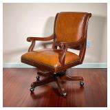 LEATHER EXECUTIVE DESK CHAIR | Rolling office chair with carved wood armrests and rivets bordering t