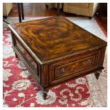 WOOD COFFEE TABLE | Dark wood coffee table with gold detailed edges, having a large drawer on two op