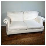 Ralph Lauren Loveseat | With white fabric upholstery, brass tacks along the bottom and scrolled arms