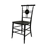 BLACK CANE CHAIR | Black cane chair with spindle legs and back with medallion in center depicting a 