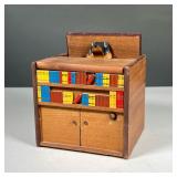 BOOKCASE MUSIC BOX | Small carved bookcase music box with small carved dog rising out of top. All co