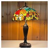 STAINED GLASS LAMP W/ORANGE FLOWERS | Molded base in a bronze color. Shade is multi-colored. - h. 28