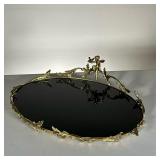 BLACK GLASS TRAY WITH ORNATE RIM | Shiny glass tray with ornate golden ring and cherub. - l. 17 x w.