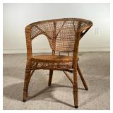 WICKER CHAIR | Antique woven wicker chair with a rounded back, armrests, and braided black accents. 