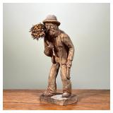 HAND CARVED WOODEN STATUE | Small, hand-carved wooden statue, depicting an elderly man carrying a bu