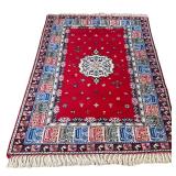 MOROCCAN CARPET | Central medallion on a red field with wide geometric border, worked in shades of r