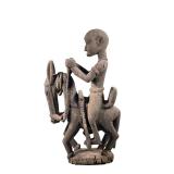 AFRICAN CARVED WOOD FIGURINE | Showing man riding horse with elongated face mounted to black stand. 