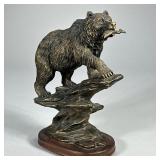 BRONZED BEAR SCULPTURE | Carved wood & bronzed bear sculpture on cliff with fish in mouth. - l. 8 x 