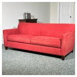 Crate & Barrel Red Sofa | With overall red textured upholstery, on dark wood tapered feet, having tw