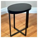 Modern Oval Side Table | Having a black wood top over metal legs. - l. 19 x w. 14.5 x h. 22 in