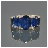 TRIPLE SAPPHIRE & 14K GOLD RING | Designed as a central oval mixed cut sapphire (9 x 6.7 x 3.7mm), f