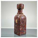 LEATHER-WRAPPED DECANTER | Embossed leather "Miguel de Cervantes" decanter with all over decoration.