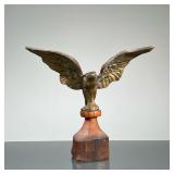 BRASS EAGLE FINIAL | Brass eagle figurine mounted on wood. - h. 7 x w. 4 x l. 7.5 in
