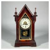 WOODEN STEEPLE-FORM SHELF CLOCK | The face with Roman numeral markers within a steepled burlwood cas