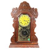 Carved Wood Shelf Clock | Ornate carved wood shelf clock, having a yellow face with Roman numeral ma