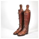 "BROWN RIDING BOOTS & FORMS | A pair of brown leather riding boots with lace holes and straps and wi