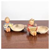 (2pc) Hummel Ashtrays | Hummel figurine ashtrays in the form of boys playing the accordion and banjo