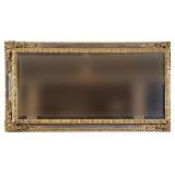 A FANCY CARVED GILT BEVELED LONG MIRROR | 19th/20th century; having a central aged mirror within a b
