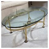 BRASS AND GLASS OVAL COFFEE TABLE | Oval beveled glass top resting on a polished brass frame with an