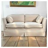 UPHOLSTERED TWO-CUSHION SKIRTED LOVESEAT WITH TOSS PILLOWS | Two-cushion loveseat upholstered in a c