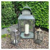 TRIO OF PATINATED METAL AND GLASS OUTDOOR LANTERNS | A collection of three outdoor lanterns comprisi