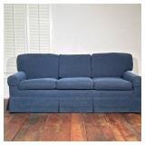 BLUE CORDUROY UPHOLSTERED THREE-SEAT SKIRTED SOFA | This lot features six hardcover reference books 