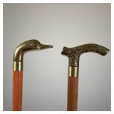 PAIR OF WOODEN CANES WITH BRASS DECORATIVE HANDLES | This pair of walking canes features polished wo