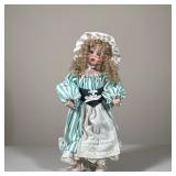 PORCELAIN COLLECTOR DOLL IN STRIPED DRESS WITH BONNET | This standing porcelain doll features curly 