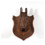 LOT 445 | LATE 19TH CENTURY CARVED WOODEN HORSE HEAD | Mounted on a shield-shaped board h. 22 w. 15 