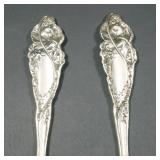 Decorated salad servers, 1899, showing female figures with putti in high relief among blooming flowe