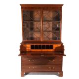 Of three part construction, the upper section with double glazed doors before three shelves with a c