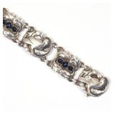  Designed as six alternating links; three with doves within a wreath, and three with sapphire caboch