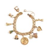 Lot 119  |  GOLD CHARM BRACELET  |  A 14k gold chain bracelet (pat 3308517) with mostly 14k charms, 