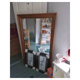 large wood framed mirror, small white book shelf, mug, framed art