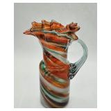A green, white, and orange crimped trim with an attached blown handle pitcher