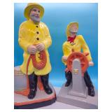 Two painted ceramic sailor figurines in yellow raincoats with nautical themes; measures 17.5"
