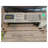 Cricut Expression 24-inch personal electronic cutter with user manual and accessories that powers on